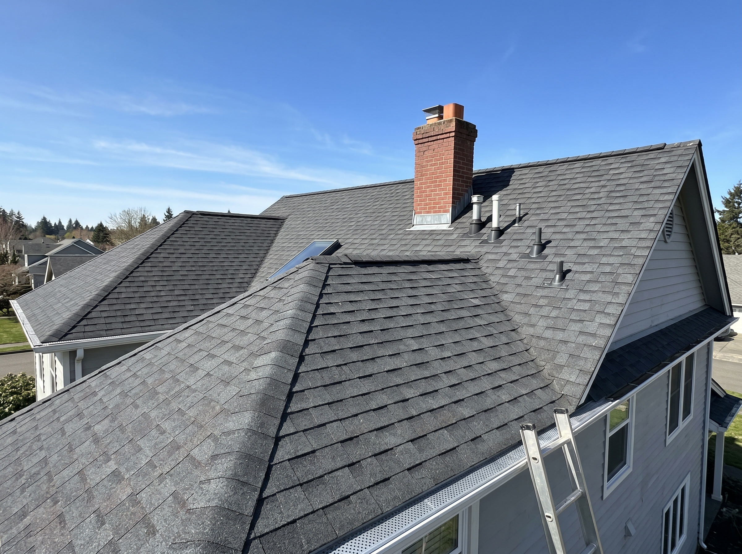 Asphalt-shingle roof showing multiple planes, a chimney, and vents.